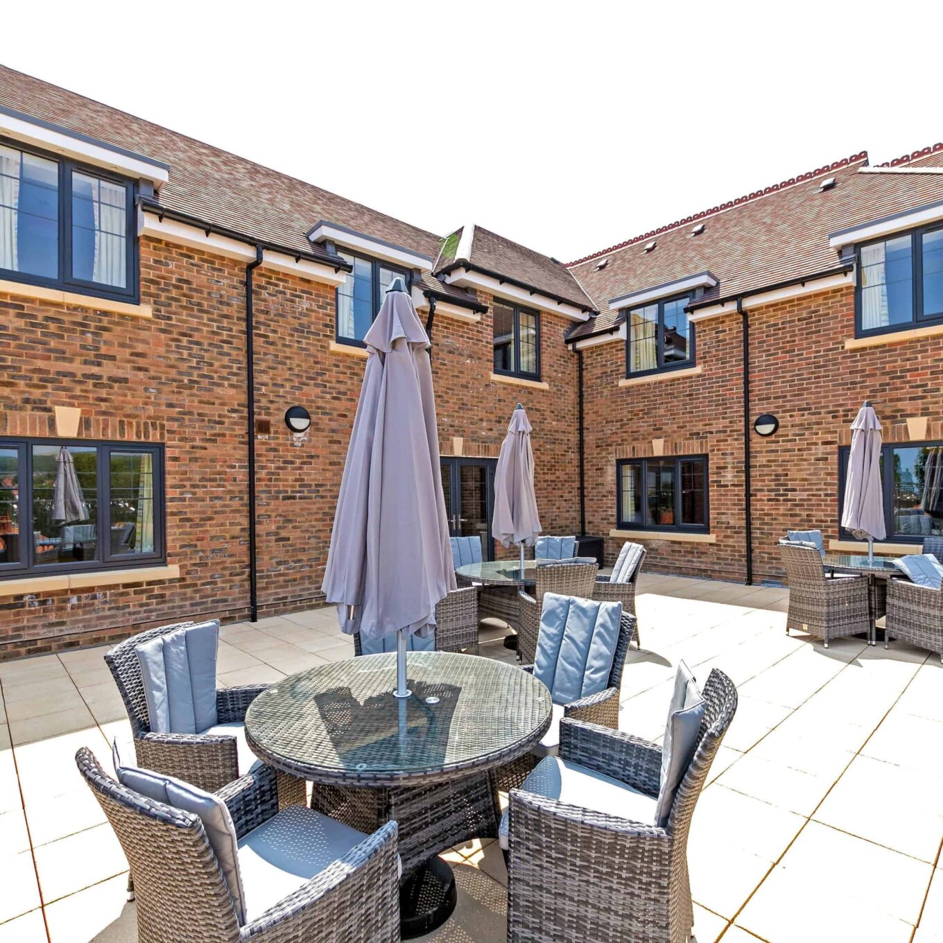 Outside patio area with seating, tables, and parasols at Beechwood Grove Care Home in Eastbourne