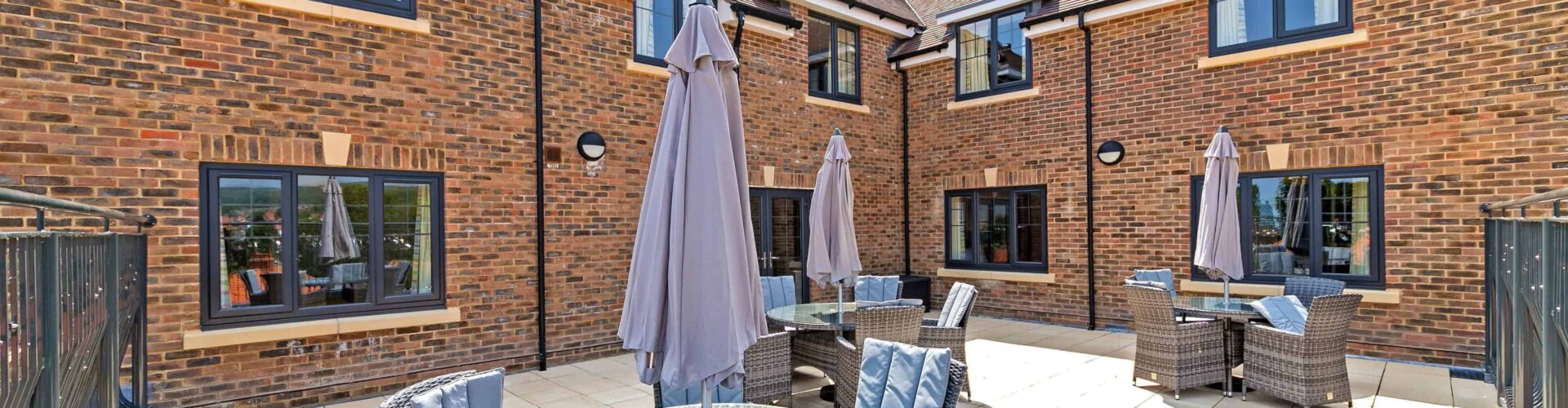 Outside terrace area with table, seats and parasol at Oakland Care Home in Eastbourne