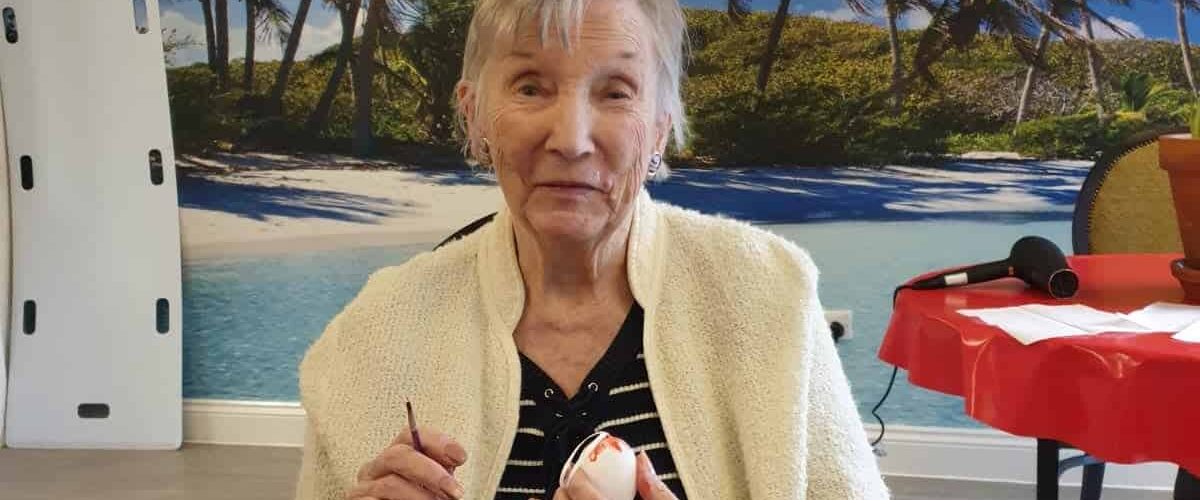 Resident smiling while painting Easter egg
