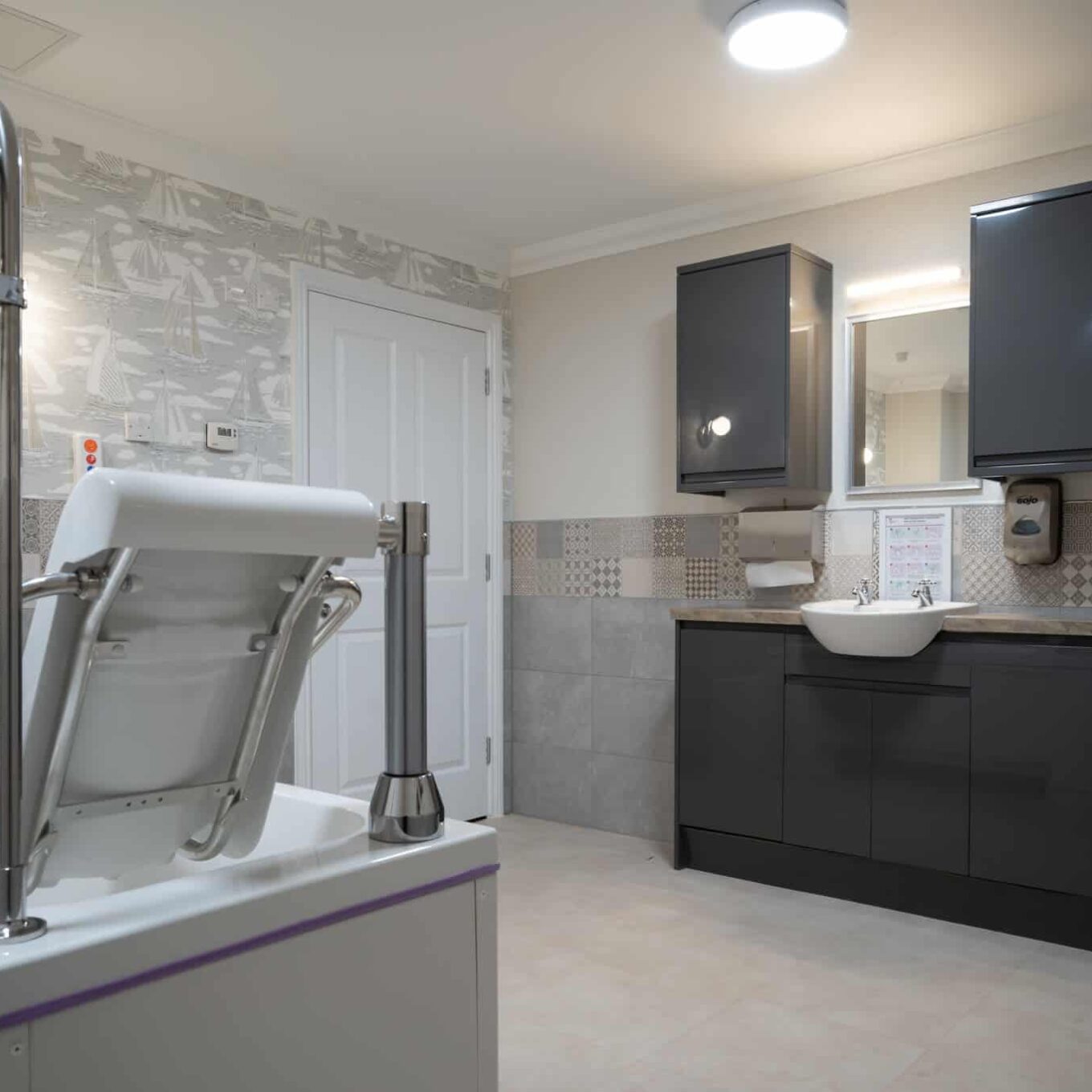 Modern bathroom with bathtub, cabinets, and toilet inside a Elsyng Care Home bathroom