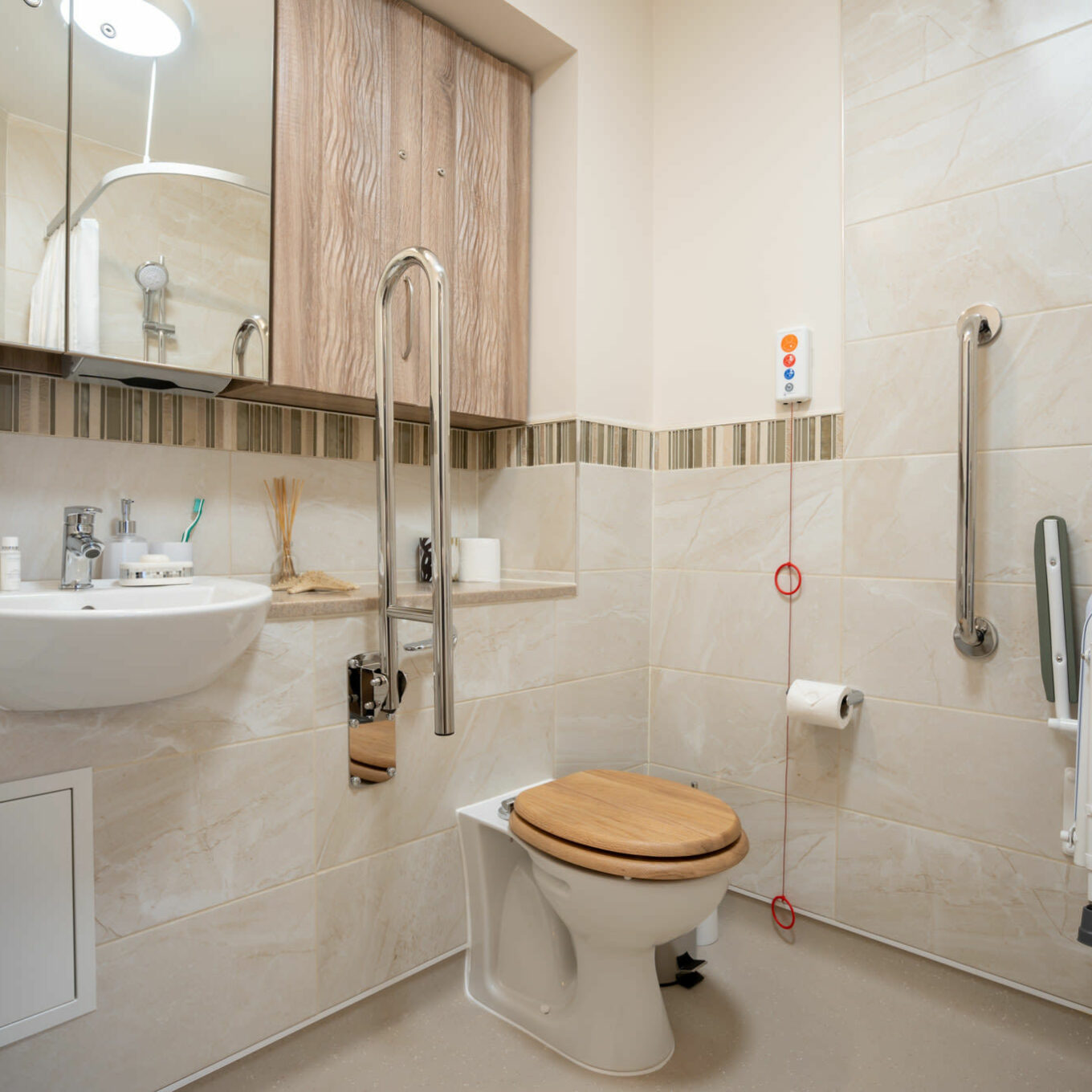 Toilet, sink and an emergency cord inside a bathroom at Elsyng Care Home in Enfield